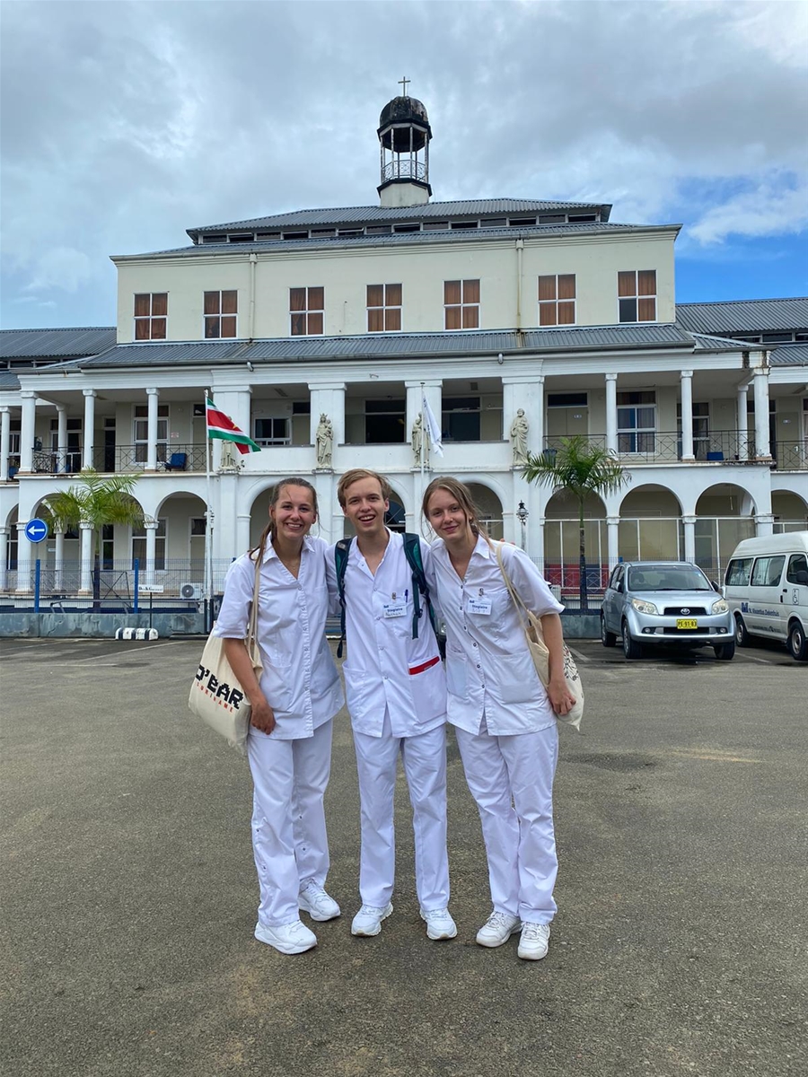 Julia van de Vijver (rechts) met Nathan Liesendahl (midden) en Eva van Beem (links) op de foto voor het ziekenhuis. Wij stonden met zijn drieën op de interne afdeling in het Sint Vincentius, Paramaribo]